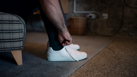 tying stylish white sneakers and suit trousers