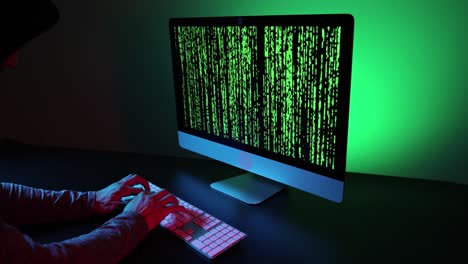 Hands typing on a keyboard and green code on a screen.