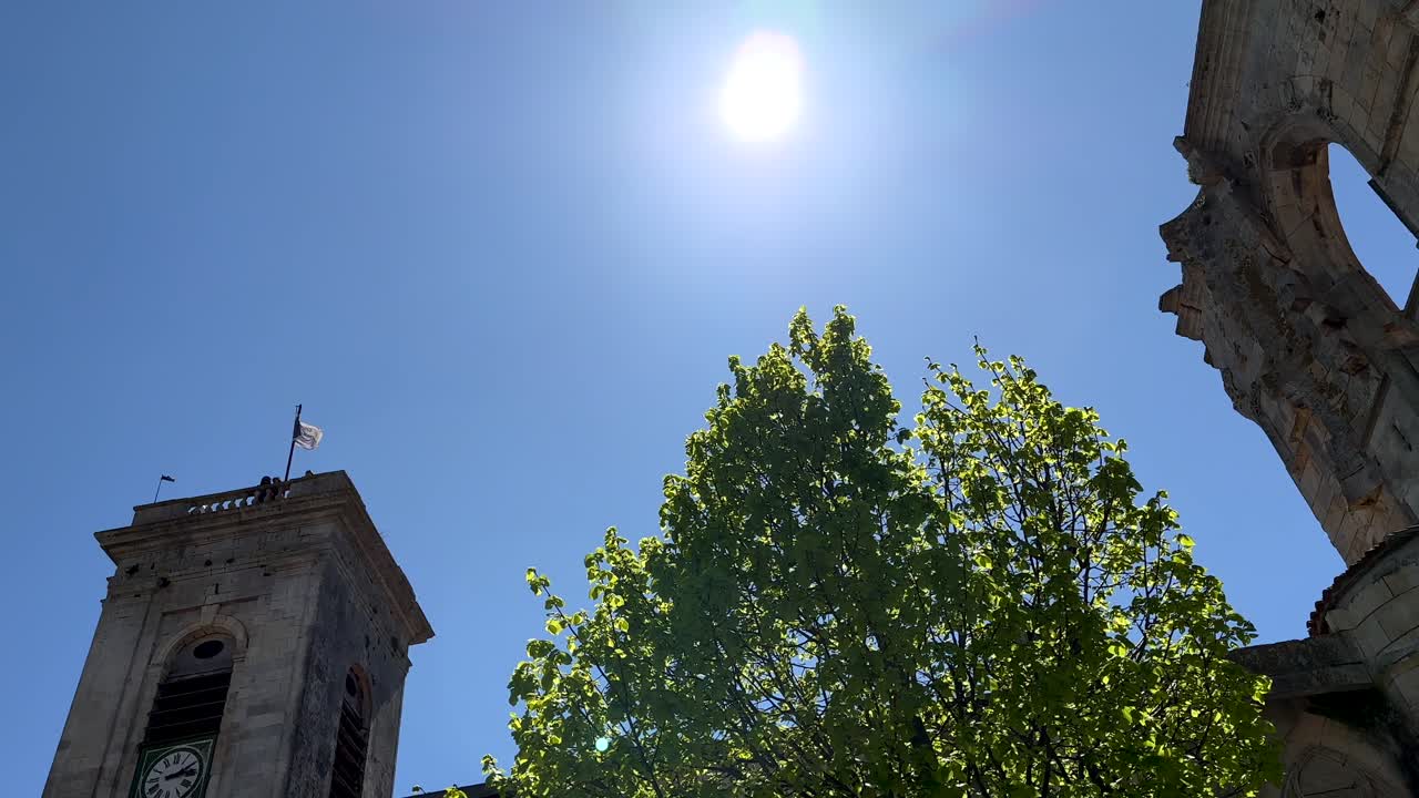 Bottom up shot showing &Eacute;glise Saint-Martin with clock tower and waving flag on il de re, France