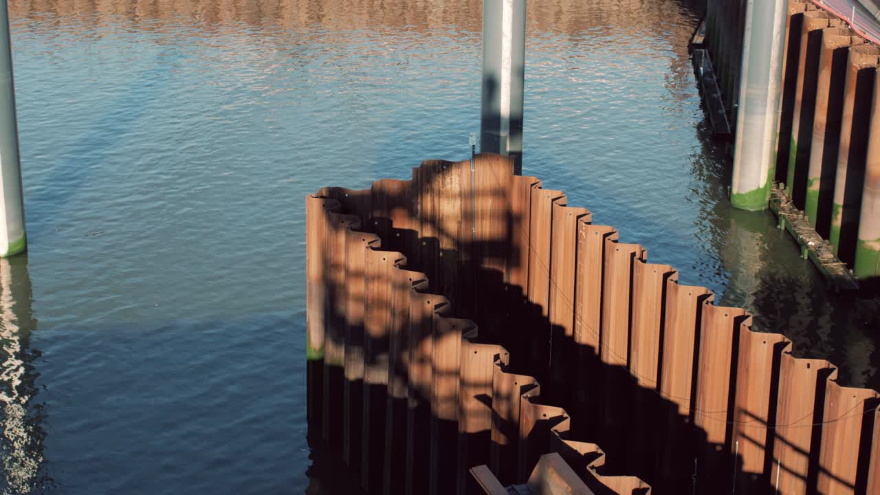 Industrial shot of rusted sheet pile walls in a waterfront construction project surrounded by calm water on a sunny day