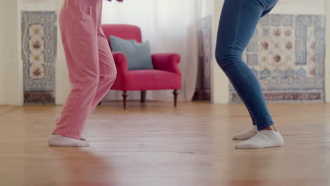 legs close up of mum and daughter dancing at home in white socks