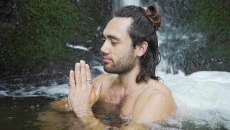 Young-man-with-long-haeir-sitting-in-a-paryer-position-in-a-spring-and-is-meditating