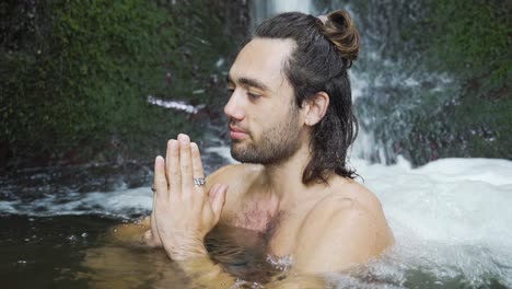 joven con cabello largo sentado en una posición paryer en un resorte y está meditando