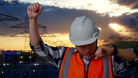 primer plano de ingeniero masculino asiático con casco de seguridad gritando gol y bailando celebrando cerca de la torre de alto voltaje