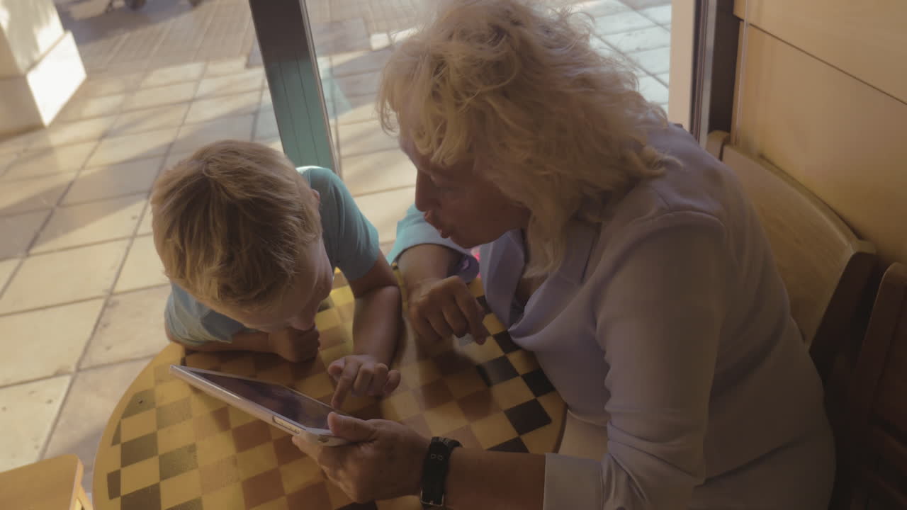 niño y abuela entreteniendo con touch pad en el café