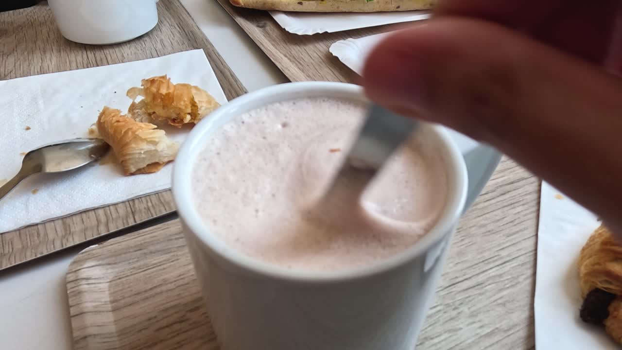 Mescolare il caffè con pasticcini sul tavolo