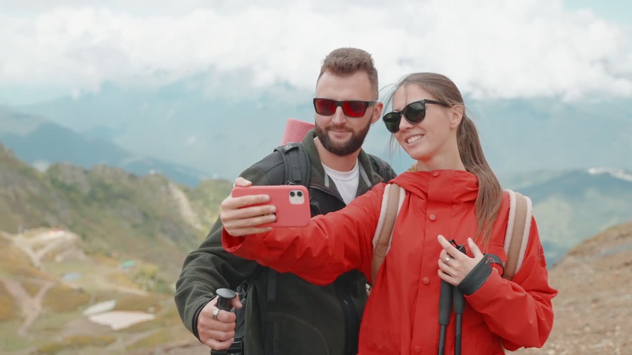 una pareja tomando selfies en las montañas.