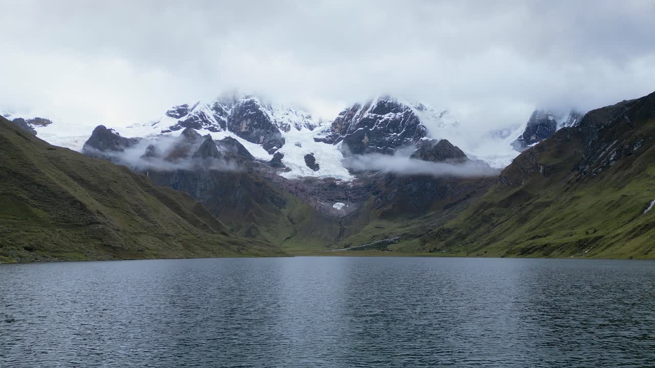Low flyover of textured Laguna Carhuacocha to snowy mtn peaks in Peru