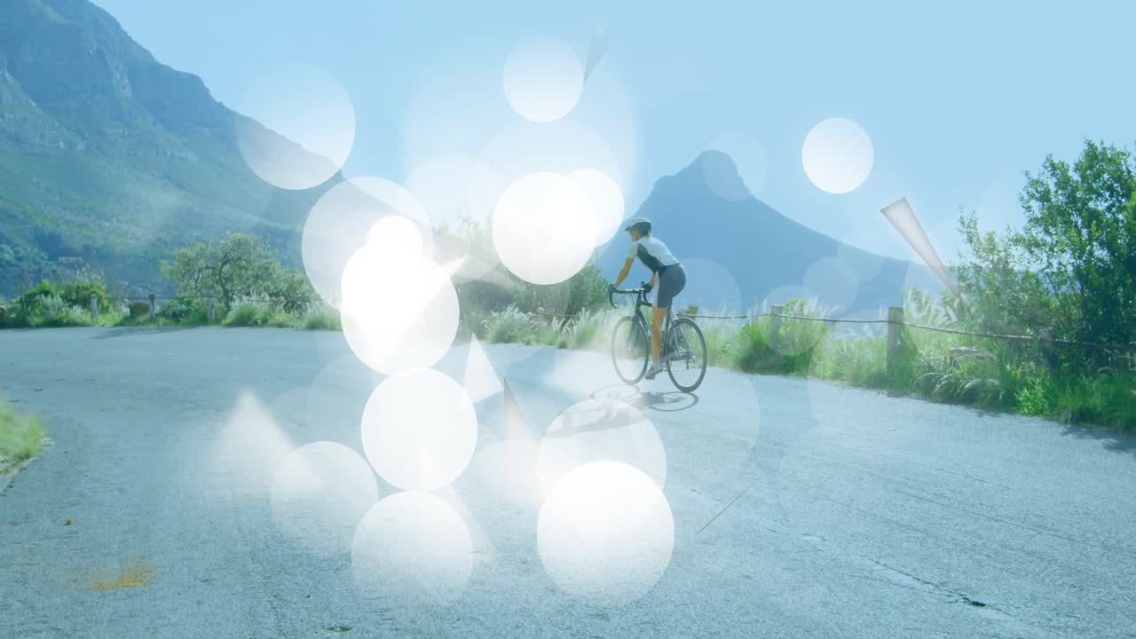 cyclist starting pedaling on road adding drifting bokeh shapes swirling then dispersing for fitness