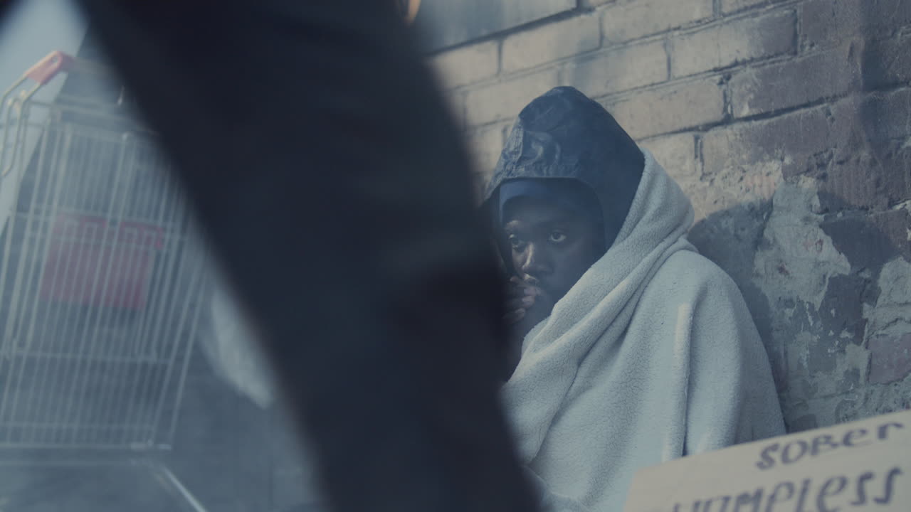 Homeless Black Man Wrapped in Blanket Shivering from Cold on Street