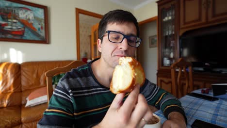 young man enjoying three king's cake with hot chocolate for breakfast