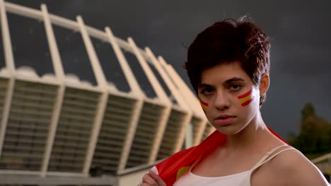 portrait of a young brunette girl soccer fan in spain, looking at the camera, serious face, evening stadium in the background 50 fps