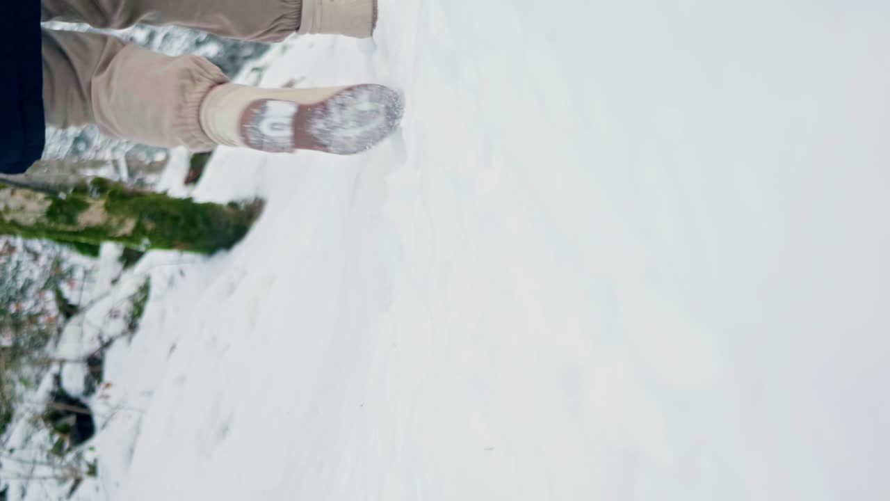 mujer caminando lejos de la cámara a través de la nieve de invierno con botas en el campo, con espacio de copia en primer plano