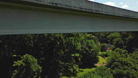 Descending-shot-of-car-on-bridge-and-green-forest-in-the-valley-during-sunny-day