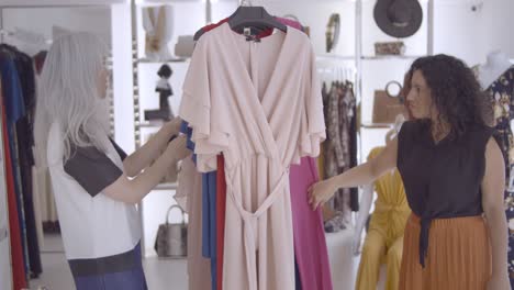 excited shop customers browsing clothes on rack