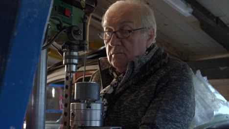 Senior-worker-preparing-drilling-machine-in-an-old-workshop