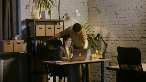 two people working on a laptop at night in an office