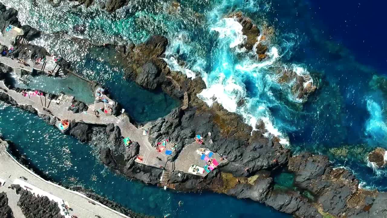 Aerial drone footage of the natural pools of Garachico Caletón. Blue ocean and the natural pools functioning as playas at Tenerife. Nice waves hit the rocks in the water.