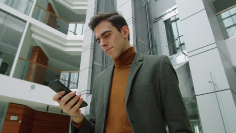 Businessman-Walking-in-Office-Center-and-Using-Phone