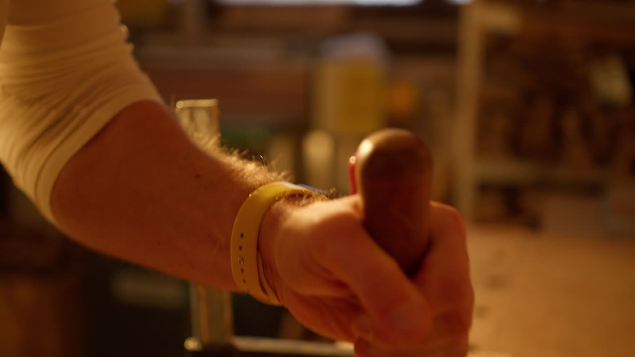 작업장에서 나무 조각을 분리하기 위해 망치질하는 남자의 클로즈업