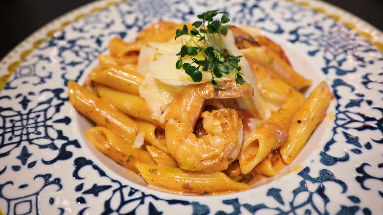 Penne seafood pasta with shrimps and parmesan cheese in a beautiful ceramic plate