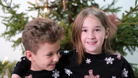 children brother and sister hugging on the background of the christmas tree children brother and sister hugging on the background of the christmas tree they are having fun at christmas children dressed in christmas sweaters video