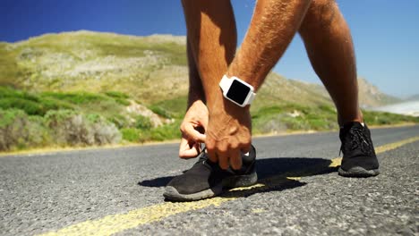 triathlete man tying his shoe lace in the countryside road