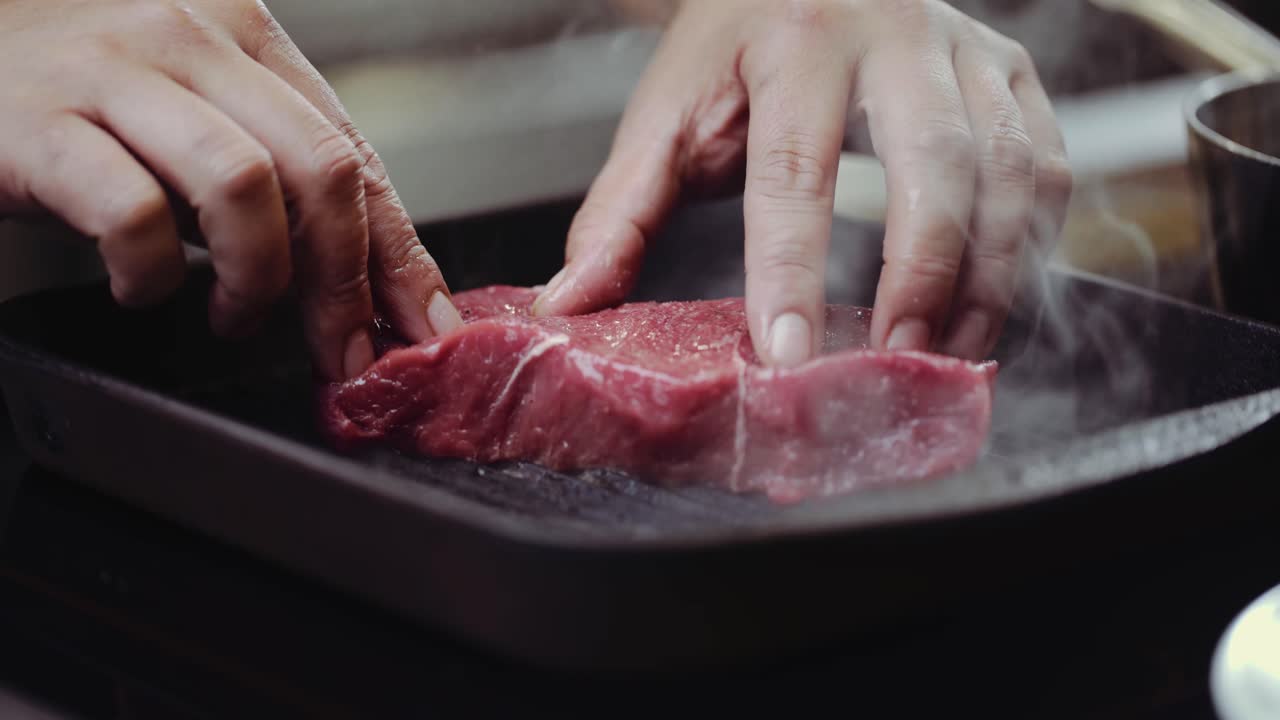 CLOSE UP: Putting steak on BBQ grill pan, pressing steak on a BBQ grill pan