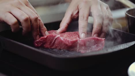 close up: putting steak on bbq grill pan, pressing steak on a bbq grill pan