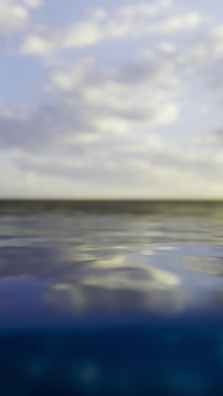 The sun sets over a tranquil ocean casting a warm glow on the water