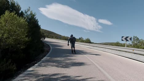 front facing follow shot of roller skater taking right turn on a mountain road