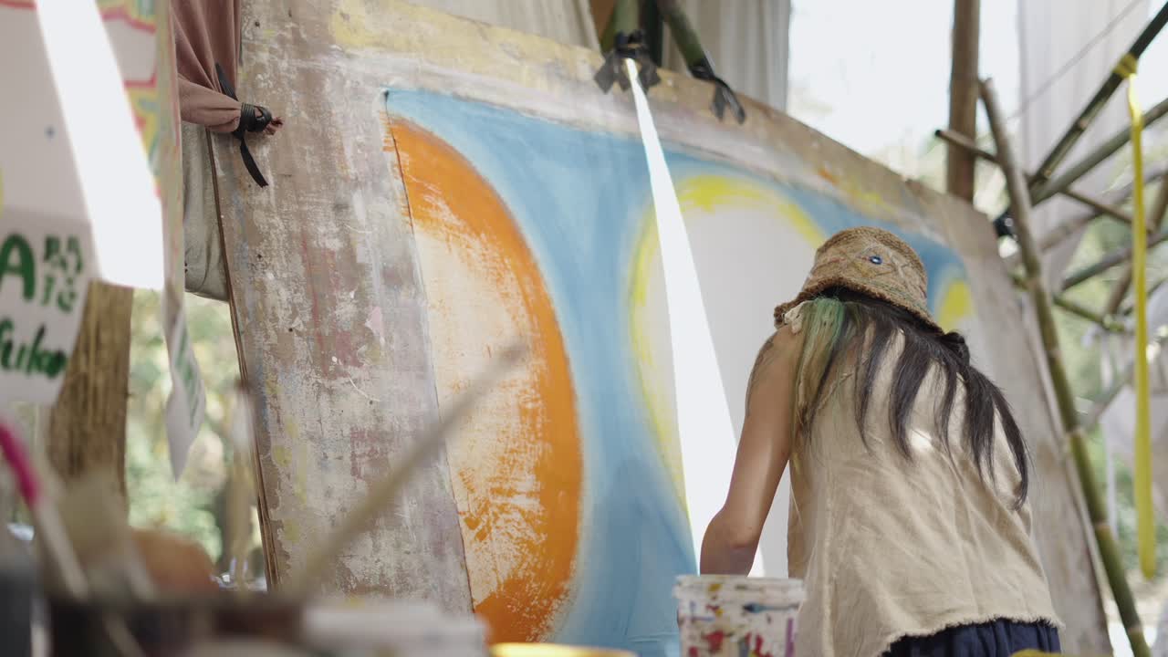Artist painting a large canvas outdoors at an art festival