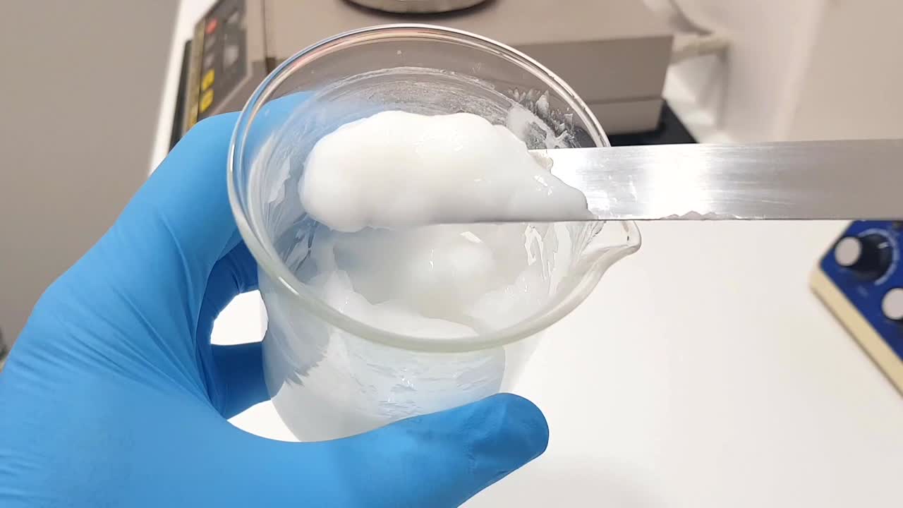 색 에션이 들어있는 컵이 스파라로 여있는 클로즈업 영상. 크림 같은 물질이 철저하게 여집니다.