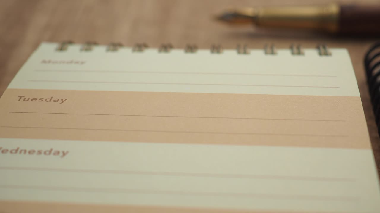 Panning Shot of a Planner with Pen and Paper Clips on a Desk