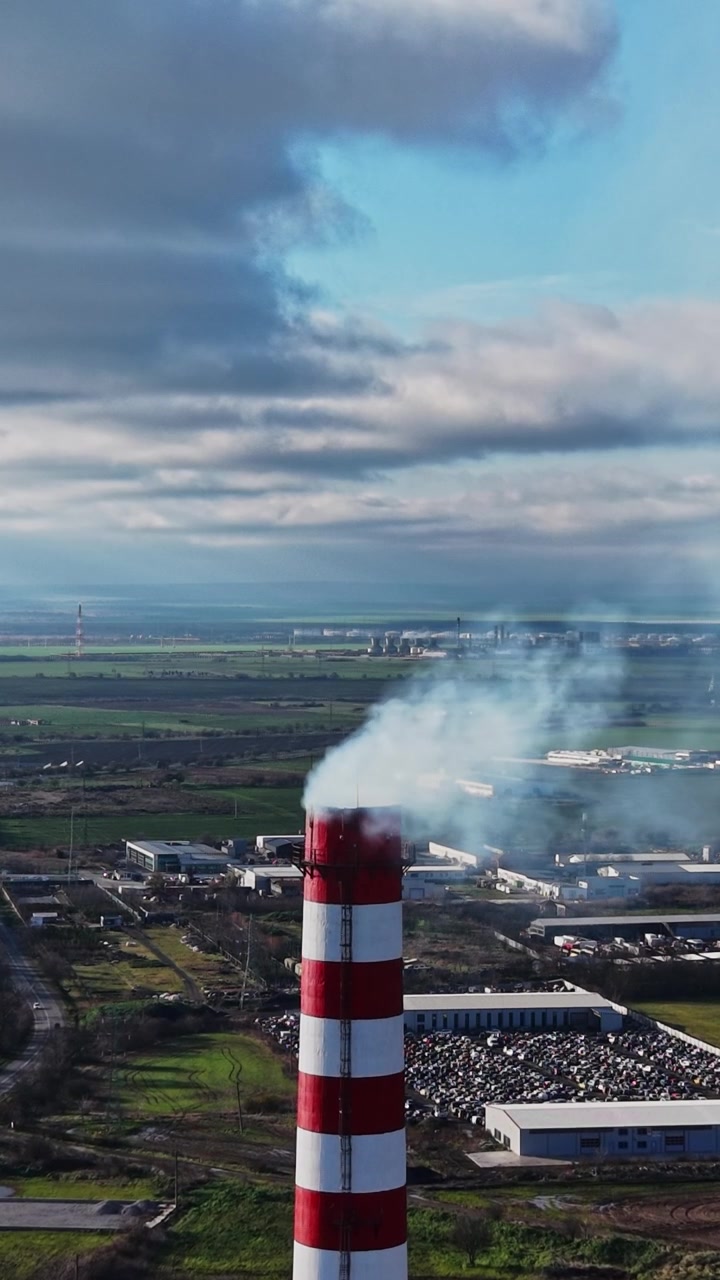 Zona industriale con ciminiere di fabbriche e cielo nuvoloso di giorno