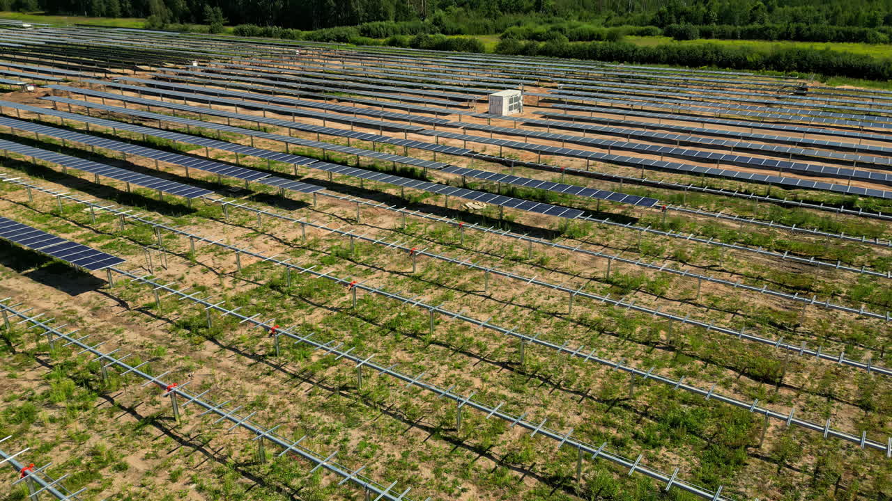 Rural fields aligned solar panels under sunshine, renewable energy resource aerial drone close up shot around green forest