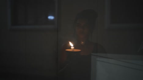 primer plano de las manos de una mujer encendiendo una vela con un fósforo en el fondo oscuro