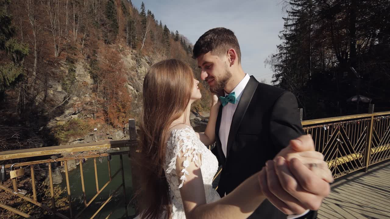 recién casados. novio caucásico con la novia bailando en un puente sobre un río de montaña