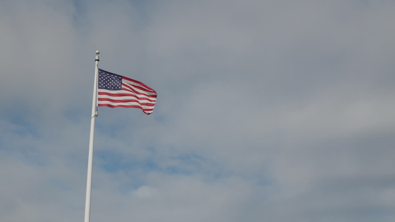 bandera estadounidense en un asta de bandera contra un cielo azul