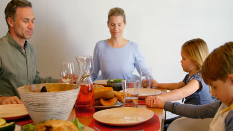 front view of caucasian family praying together at dining table in a comfortable home 4k