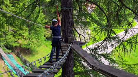 slow motion rearview children crossing a via ferrata in alta badia, italy, a scenic adventure in the dolomites forest balancing on wooden bridge between trees