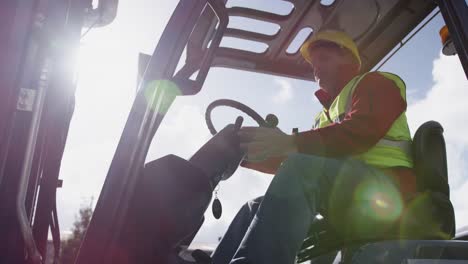 Warehouse-worker-driving-forklift-outside-factory