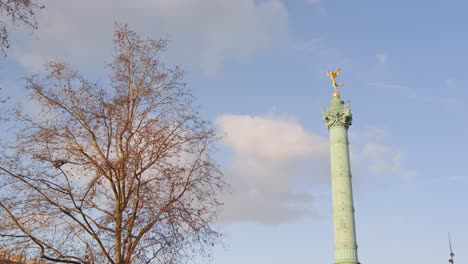 Golden-statue-of-tall-tower-in-Paris,-autumn-tree-colors,-handheld