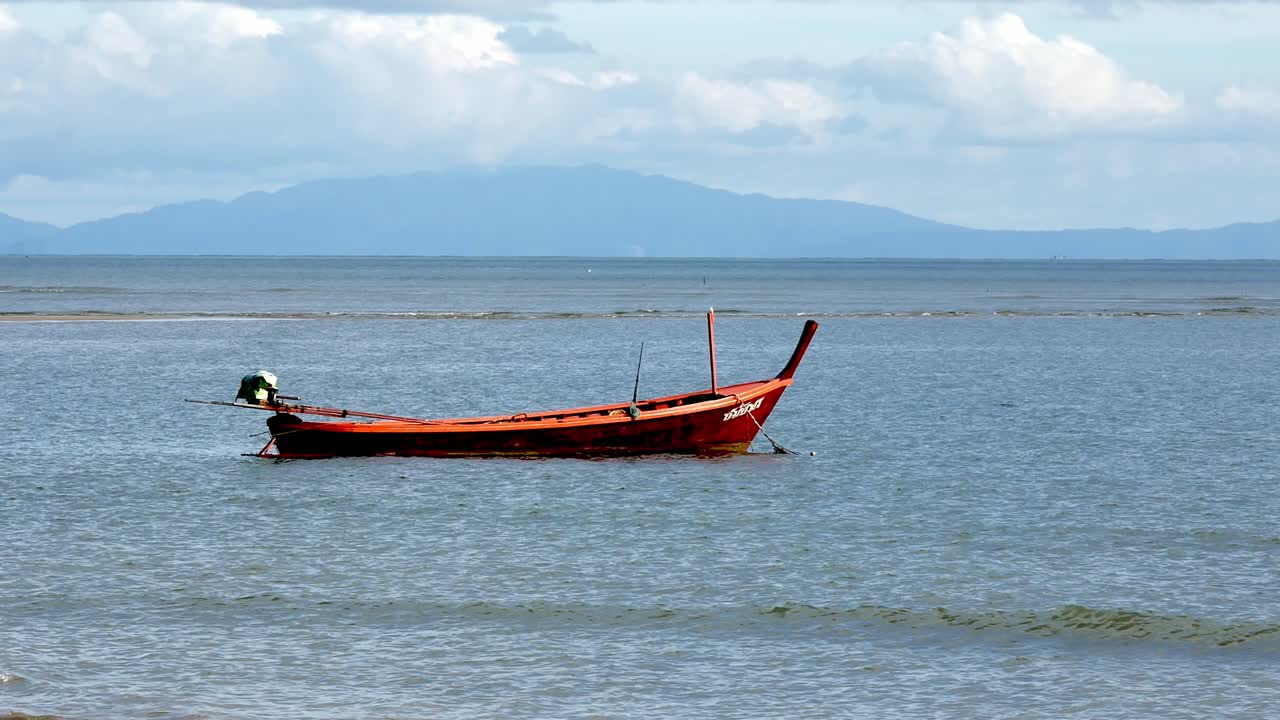 vista de los barcos de pesca amarrados a lo largo de una playa azotada por el viento durante el día en el sur de tailandia