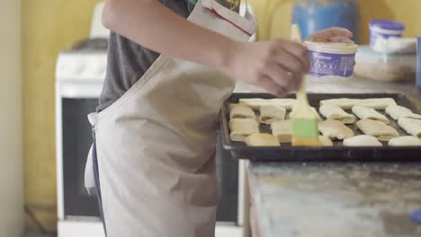 a pastry chef uses a brush to moisten dough with water or egg wash, ensuring an even browning during baking