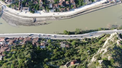 Drone-view-in-Albania-flying-over-Berat-medieval-town-showing-brick-houses,-river-and-mountain