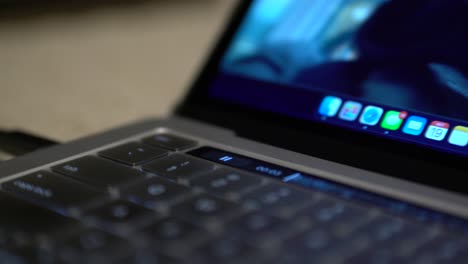 close up finger pressing play touchbar on laptop touch bar strip above keyboard