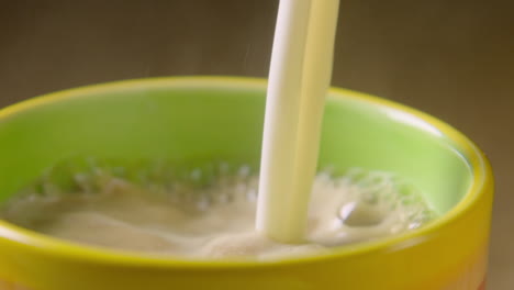 Sartén-A-La-Izquierda,-La-Leche-De-Avena-Espumosa-Se-Vierte-En-Una-Taza-Humeante-De-Colores,-60-Fps