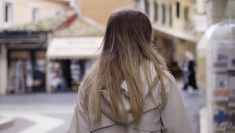 a woman walks along and old city street, looks around at the sights