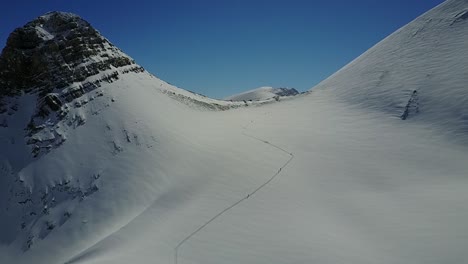 drone flying over backcountry skiers ascending towards ridgeline